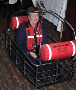 Commander Sandy Thomas volunteered to demo the safety basket during a presentation by Andrew Johnston of the Port Angeles Coast Guard